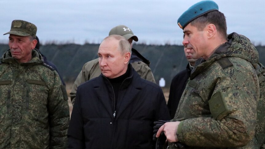 身穿黑色外套的普京站在军方官员的两侧。